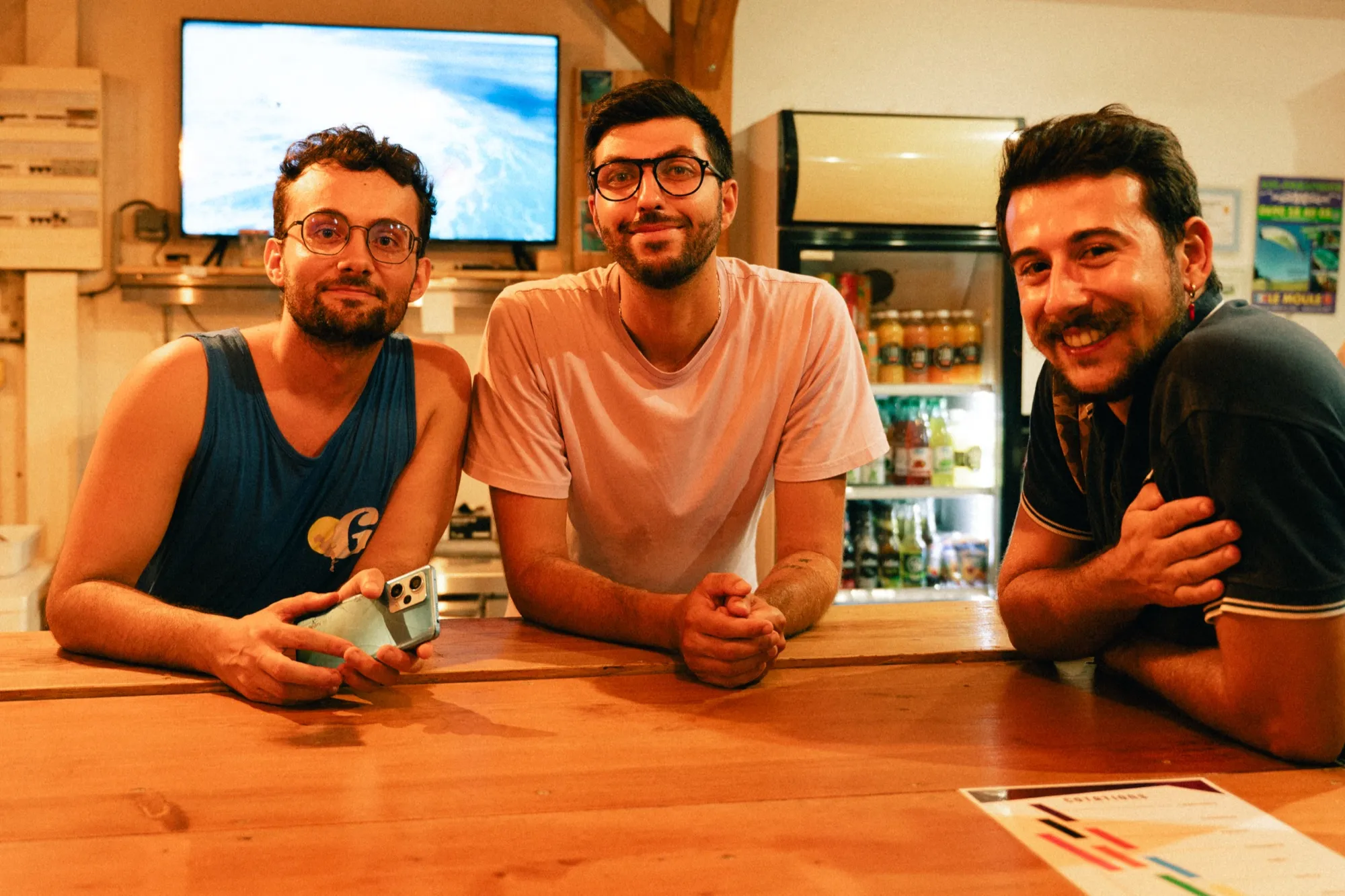 Trois amis souriants accoudés au comptoir du ravito